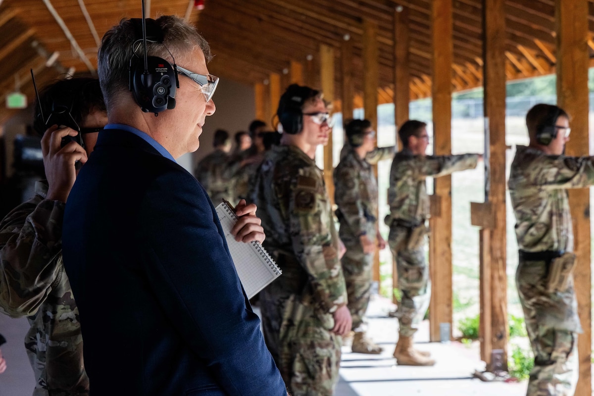 The Secretary of the Air Force observes Airmen participating in target practice at a firing range.
