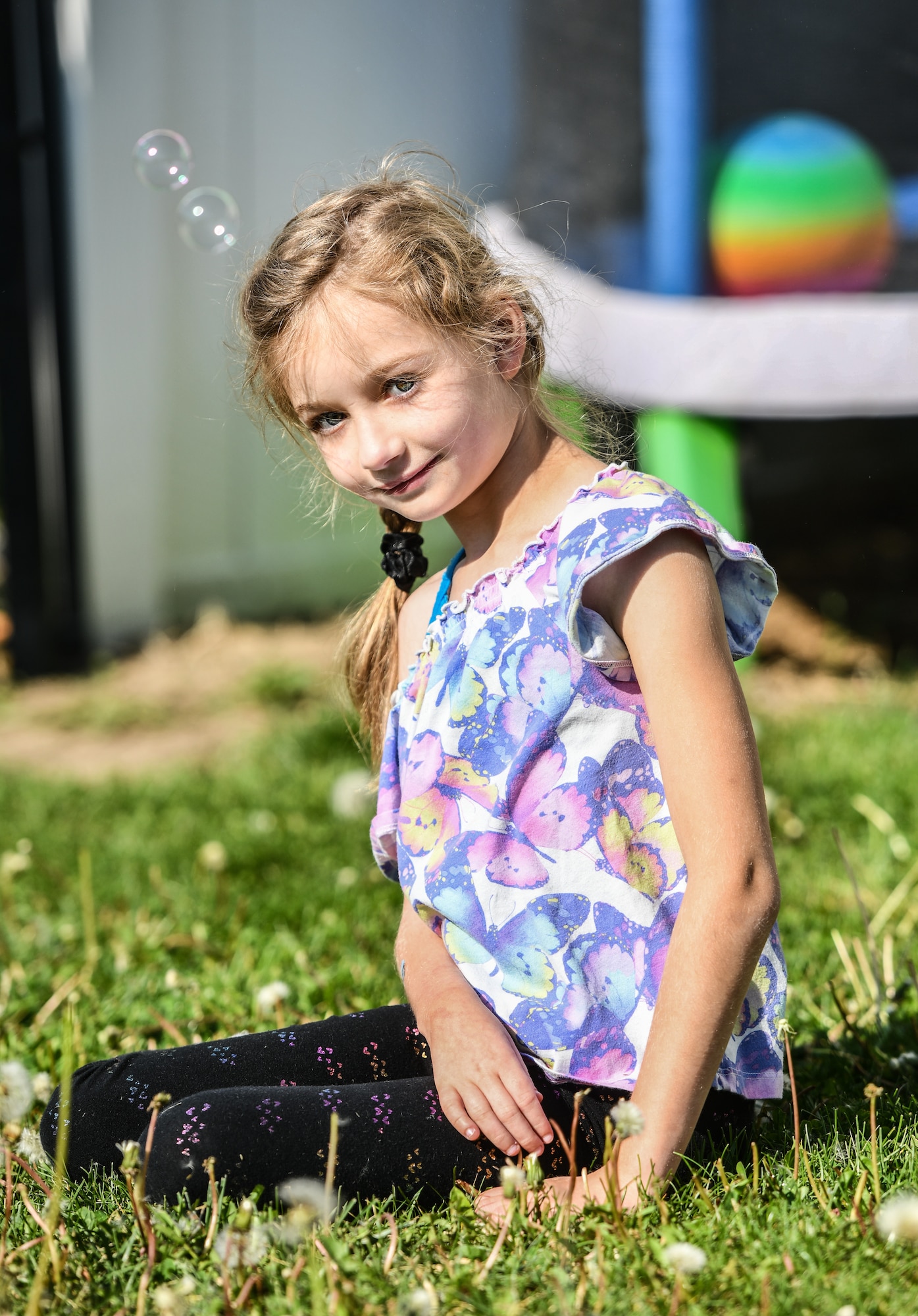 Hannah sits in her backyard while bubbles float by on April 24, 2026. One of Hannah's favorite activities is playing outside(U.S. Air Force photo by Chad Watkins)