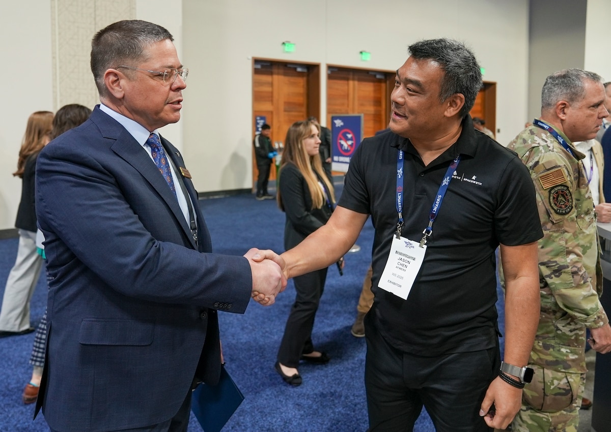 Jason Chen, AFWERX program manager, shakes hands with an attendee during the Warfare Symposium at the Gaylord Rockies Resort and Convention Center in Aurora, Colorado, Feb. 23, 2026.