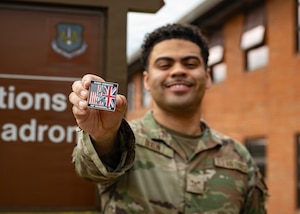 U.S. Air Force Airman 1st Class James Dixon, 100th Operations Support Squadron aircrew flight equipment technician, holds a Team Mildenhall challenge coin after being recognized as the 100th Air Refueling Wing’s Ready Airman at RAF Mildenhall, England, April 27, 2026.