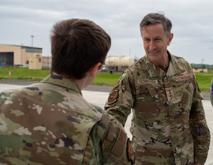 A general shakes the hand of an Airman.