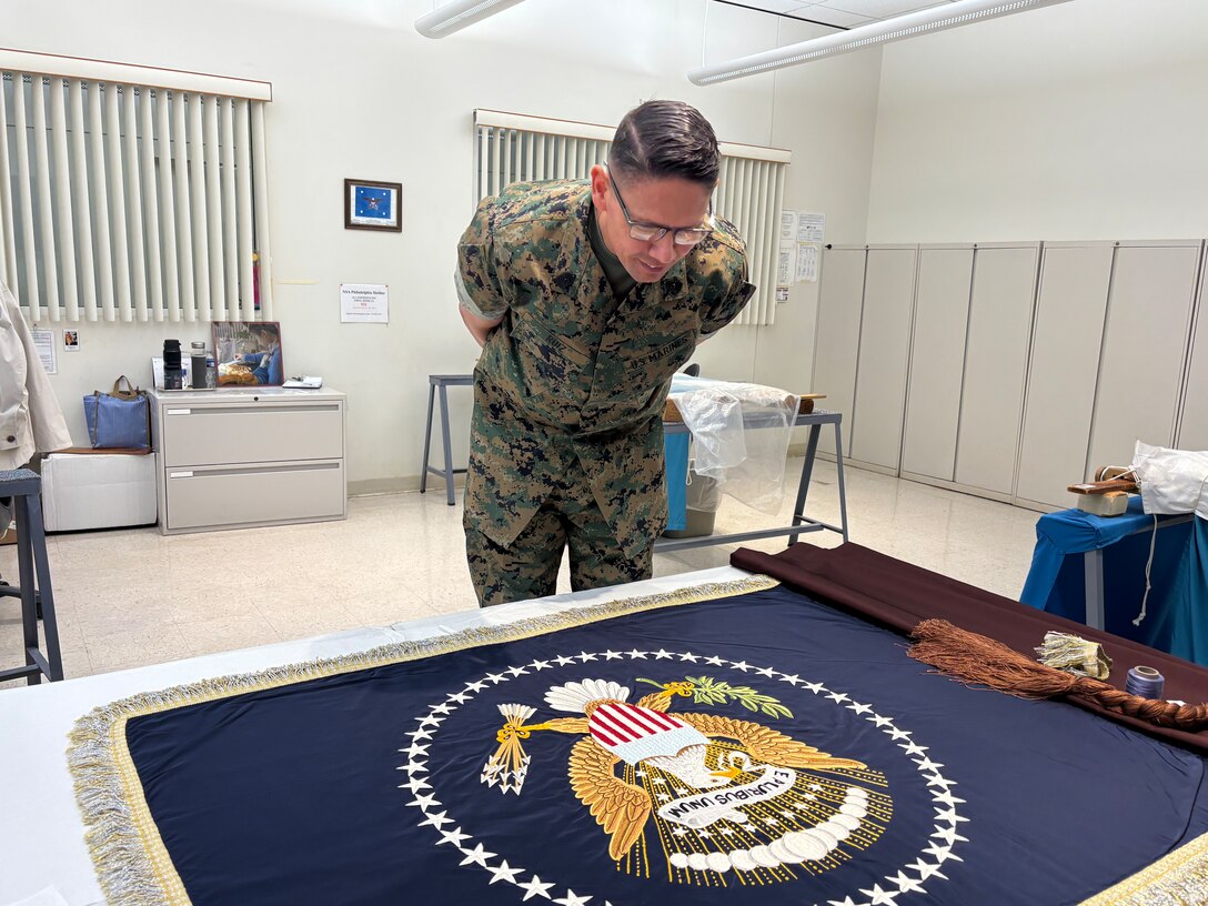 Sergeant Major of the Marine Corps Carlos Ruiz examines a nearly completed Presidential flag during a visit to Defense Logistics Agency Troop Support in Philadelphia on April 27. His visit included a tour of the flag room.