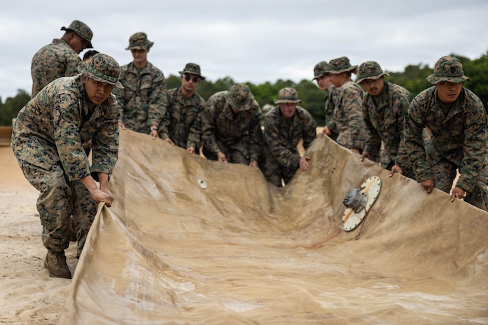 U.S. Marines with 8th Engineer Support Battalion, Combat Logistics Regiment 27, 2nd Marine Logistics Group, drag a bladder during an air-delivered ground refueling site set up as part of a large multi-modal field exercise at Marine Corps Base Camp Lejeune, North Carolina, April 27, 2026. The purpose of this exercise is to train and evaluate the platoon's ability to provide distributed and expeditionary class III resupply from an expeditionary advanced base. (U.S. Marine Corps photo by Sgt. Alfonso Livrieri)