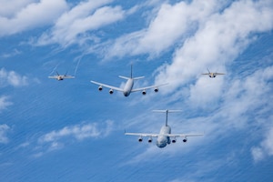 Airmen assigned to the 154th Operations Group, 154th Wing, Hawaii Air National Guard, operate U.S. Air Force aircraft during a multi-ship formation flight off the coast of Hawaii, Jan. 5, 2026. The formation included a C-17 Globemaster III assigned to the 15th Wing, and a KC-135 Stratotanker and two F-22 Raptors assigned to the 154th Wing, demonstrating total force integration and synchronized airlift, aerial refueling and fighter capabilities. (U.S. Air National Guard photo by Senior Master Sgt. Mysti Bicoy)