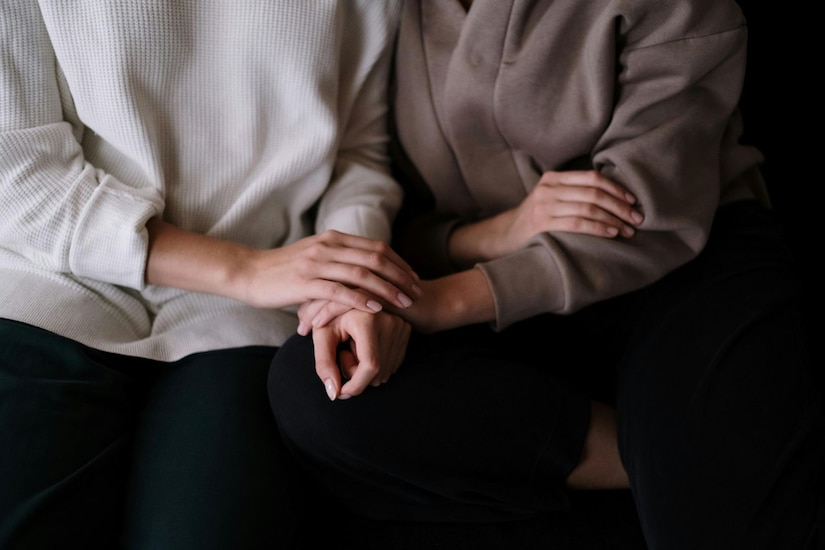 Torsos of two people embracing while wearing sweaters with neutral tones.