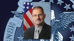 Graphic featuring an official photo of a man wearing a gray buttoned shirt, gray tie and dark gray blazer