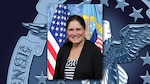 Graphic featuring an official photo of a woman with dark hair in a ponytail, wearing a striped shirt and black blazer