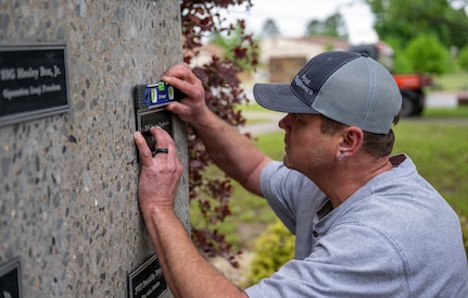 Arkansas Deptartment of the Military employee Kevin Shaffer installs a plaque April 29, 2026, that honors Pfc. James Reginato who was injured by enemy fire in Mignano, Italy, on Dec. 15, 1943.