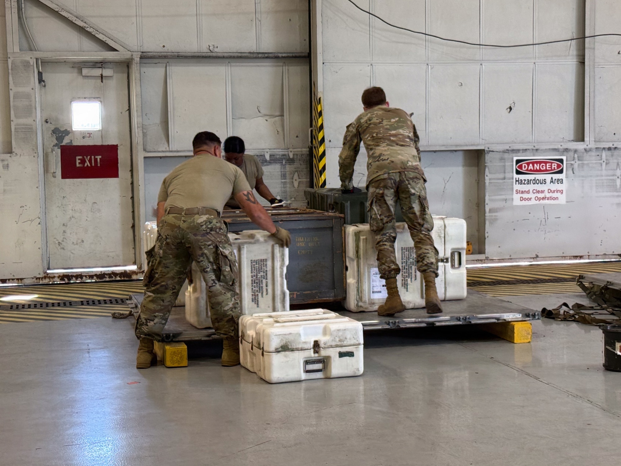 Three Airmen working on a pallet and equipment.