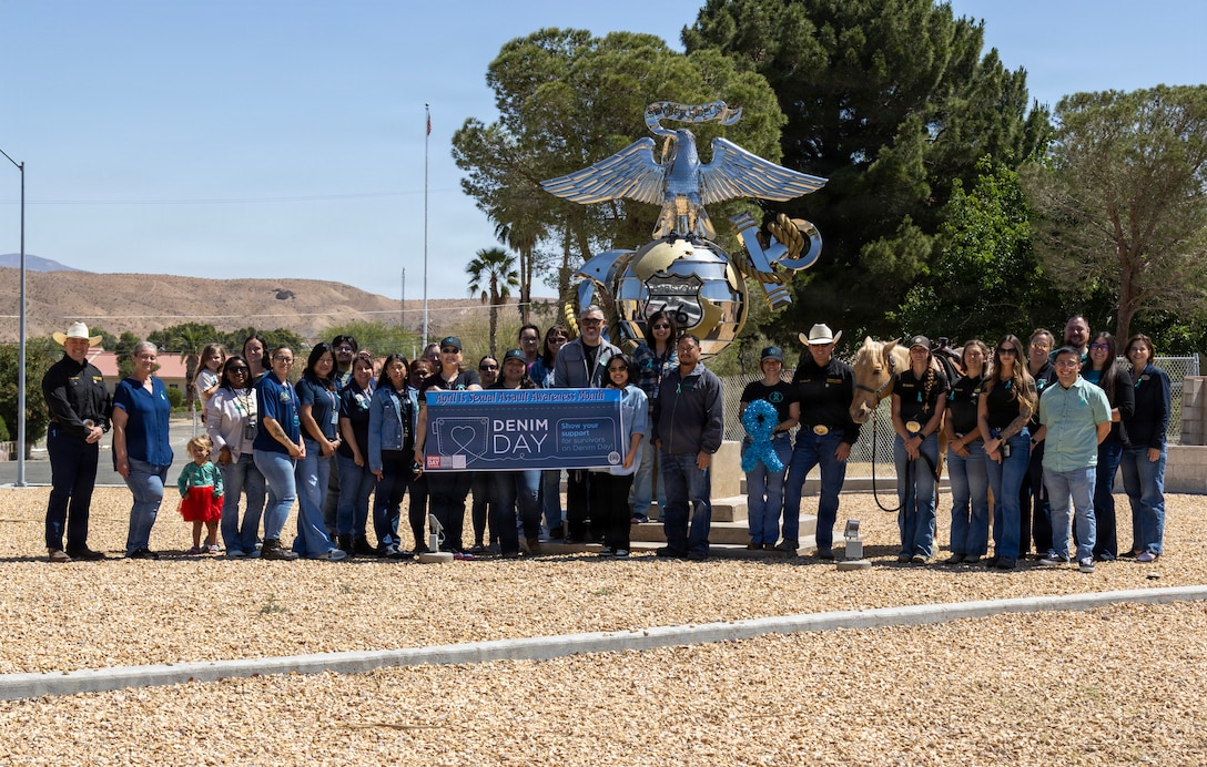 Colonel Russell Savatt, base commanding officer, Sunny from  Marine Corps Mounted Color Guard , along with serval base personnel joined MCCS Barstow Behavioral Health in a group photo sporting their denim in front of the Eagle, Globe, and Anchor statue aboard Marine Corps Logistics Base Barstow, California, April 29. Individuals participate by wearing jeans to challenge victim-blaming perspectives and to express support for survivors. This initiative originated from a 1990s ruling by an Italian court that erroneously suggested that wearing tight jeans indicated consent.