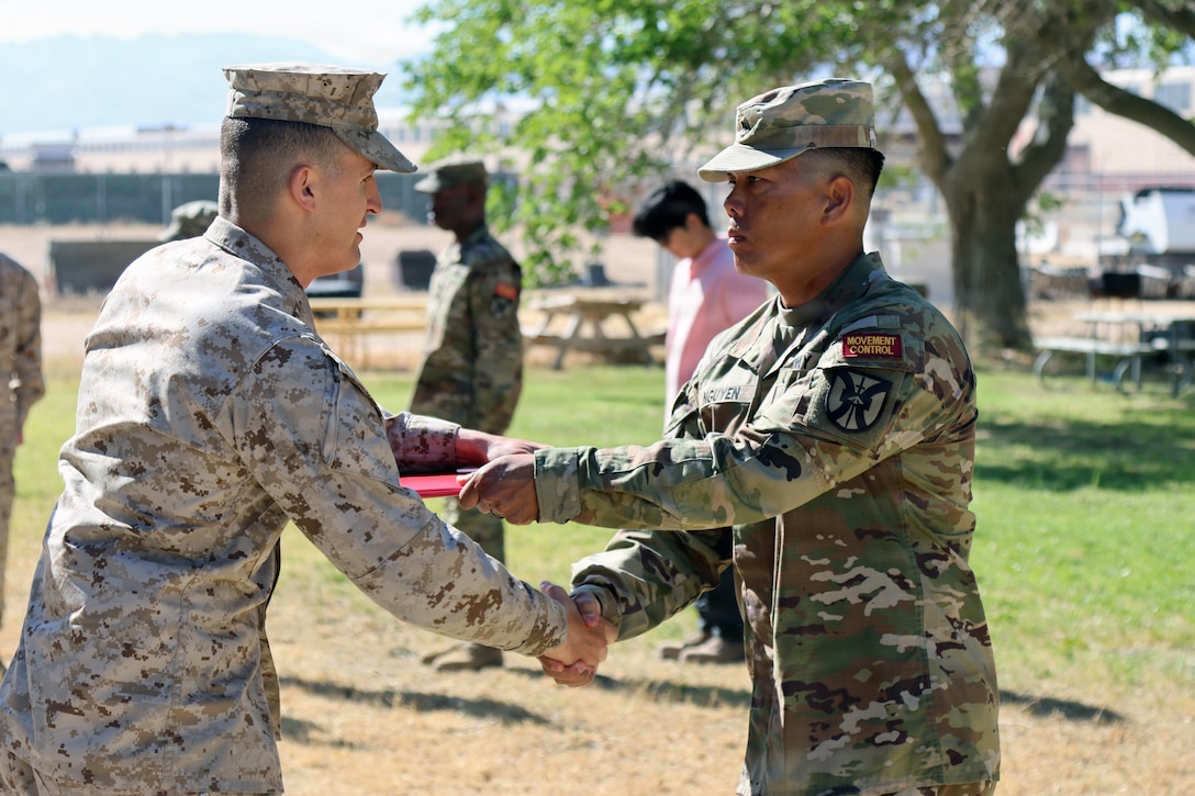 Captain William Bomchill, S3A & Range Control Officer and Antonio Flores, RHOG-TC Lead Instructor, distribute awards to Railhead Operations group Training Class 26-04 graduates at Yermo Annex aboard Marine Corps Base Barstow, California April 30th