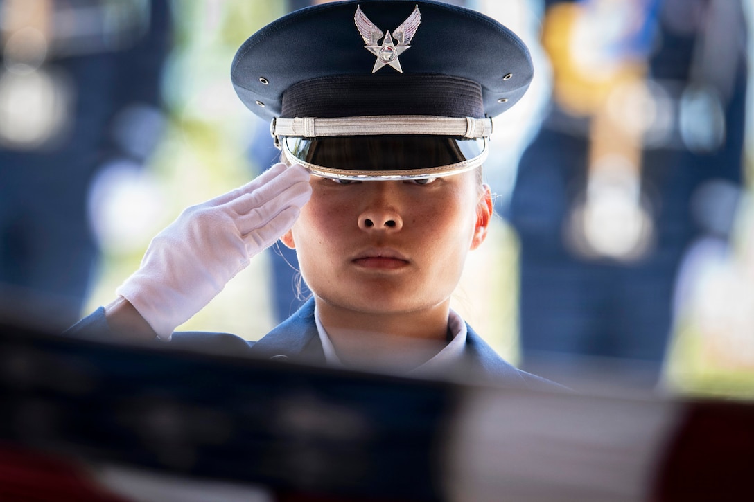 A close-up of an airman saluting against a blurred background.