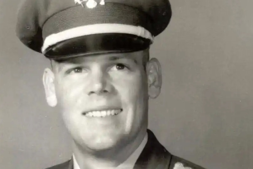 A man wearing a military dress uniform smiles for a picture.