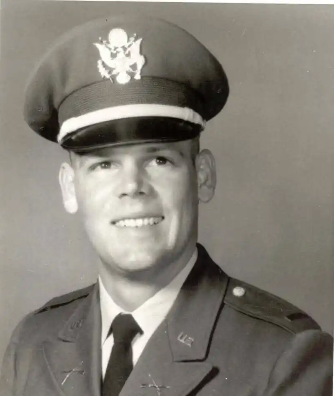 A man wearing a military dress uniform smiles for a picture.