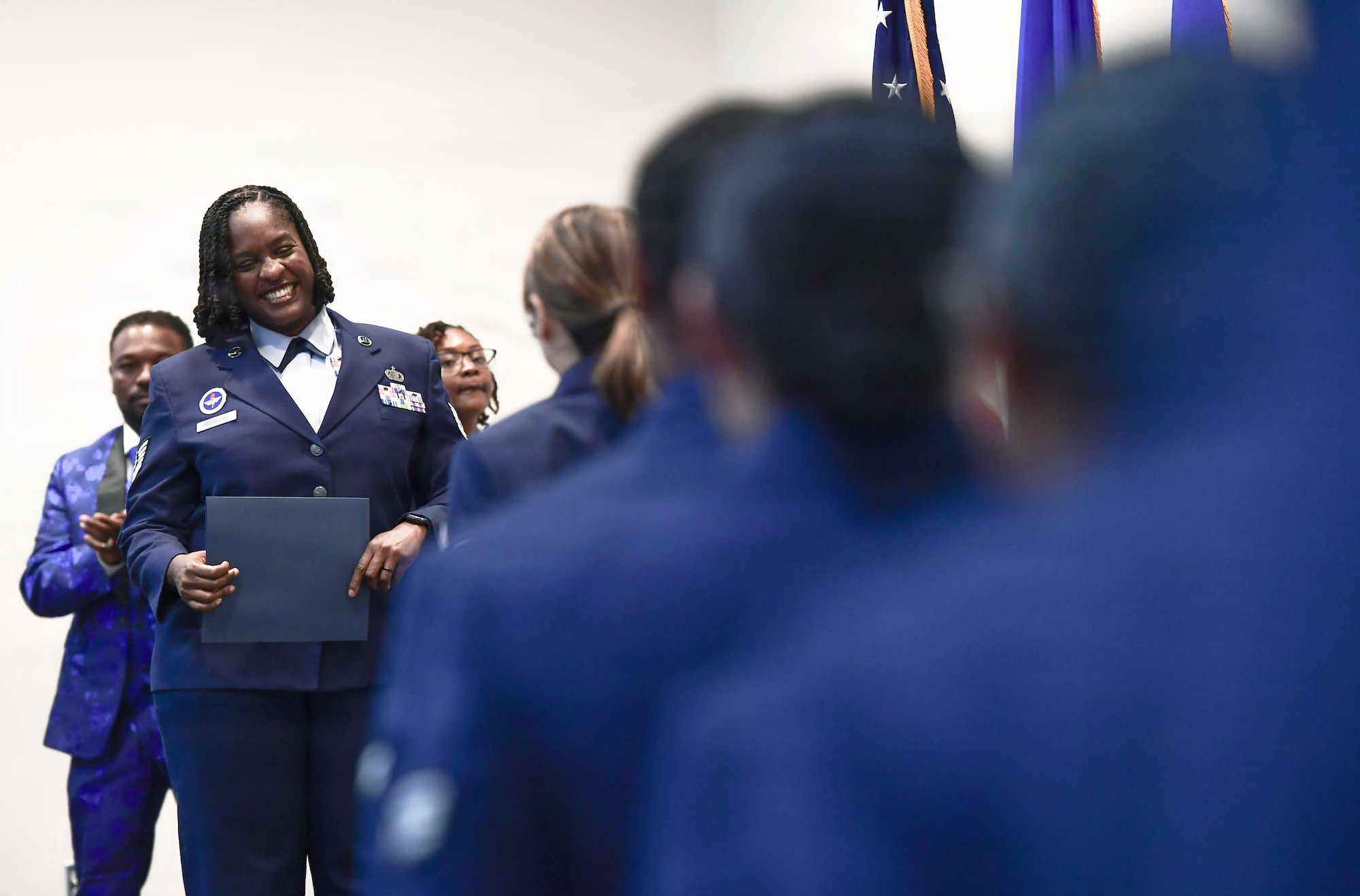 An Air Force woman holds a certificate on stage.