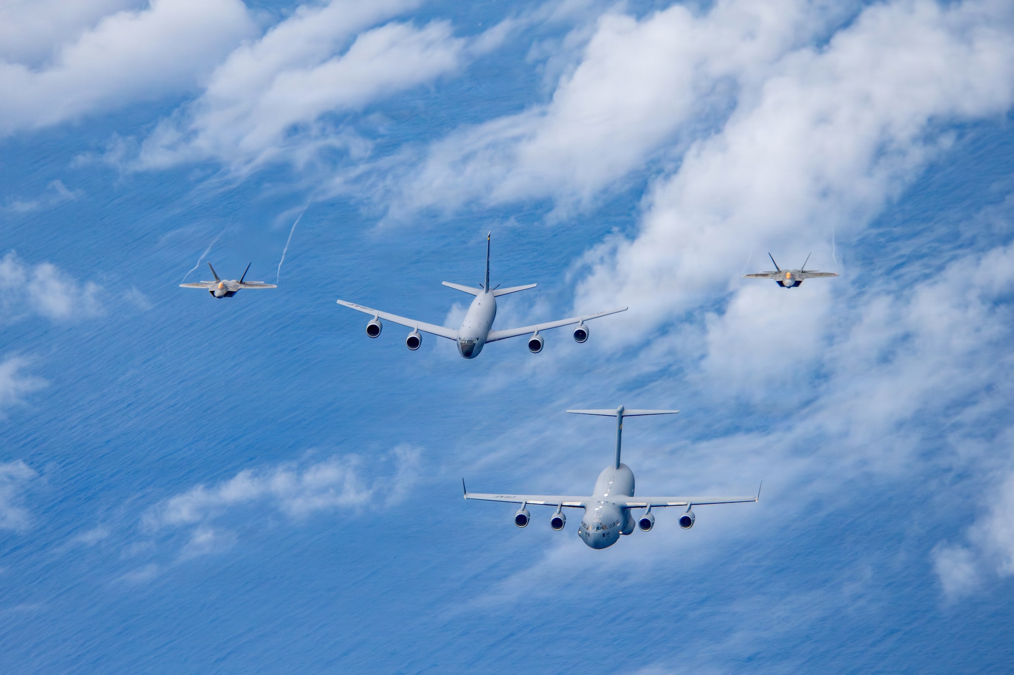 Airmen assigned to the 154th Operations Group, 154th Wing, Hawaii Air National Guard, operate U.S. Air Force aircraft during a multi-ship formation flight off the coast of Hawaii, Jan. 5, 2026. The formation included a C-17 Globemaster III assigned to the 15th Wing, and a KC-135 Stratotanker and two F-22 Raptors assigned to the 154th Wing, demonstrating total force integration and synchronized airlift, aerial refueling and fighter capabilities. (U.S. Air National Guard photo by Senior Master Sgt. Mysti Bicoy)