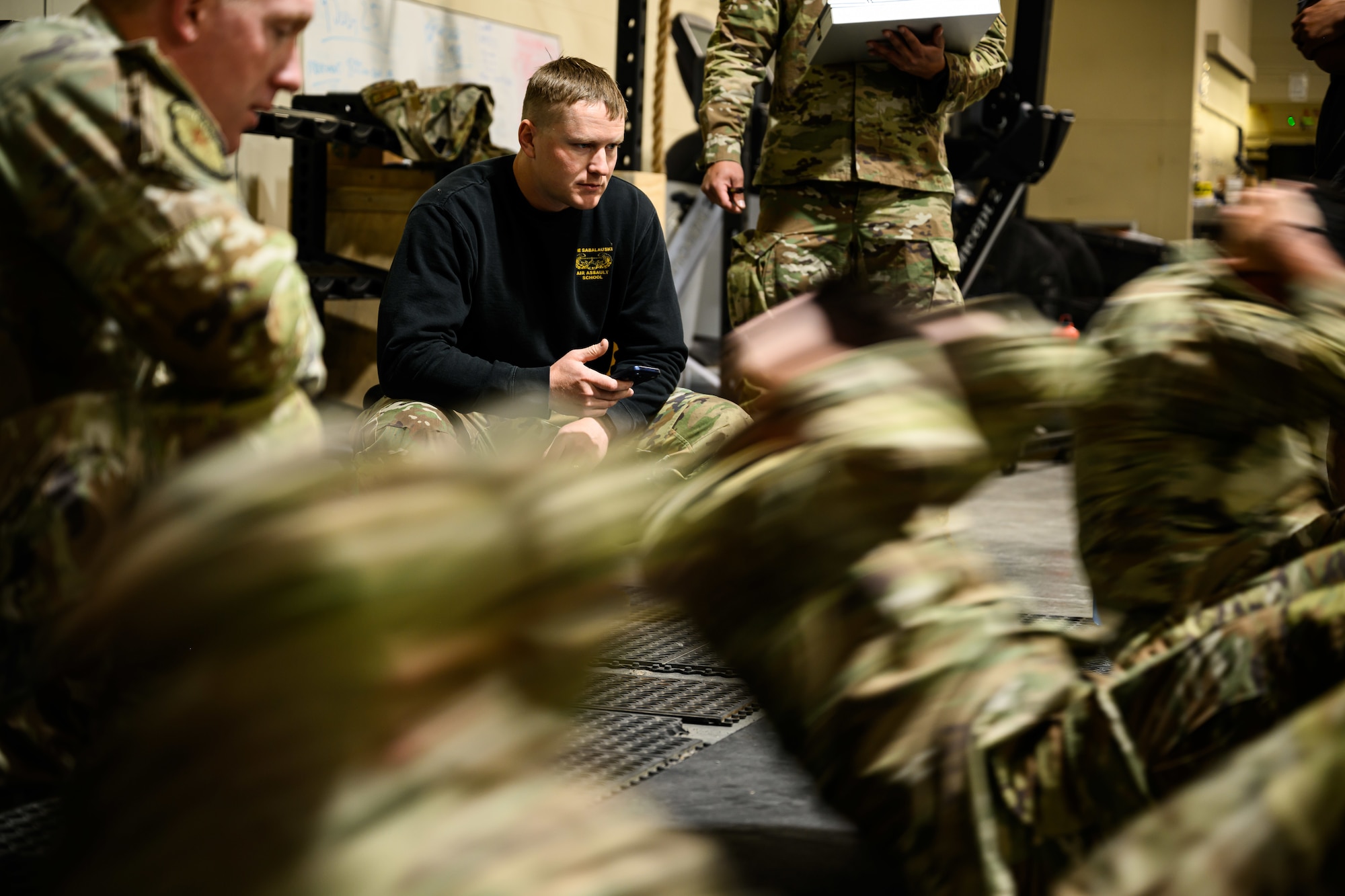 Tech. Sgt. Timothy Bukovich crouching down behind Airmen doing sit-ups.