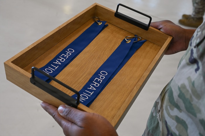 U.S. Air Force Master Sgt. Mark Knight, 55th Rescue Squadron aviation resource management superintendent, proffers two new Operation Allies Refuge streamers during a Presidential Unit Citation ceremony at Davis-Monthan Air Force Base, Arizona, April 17, 2026. The streamers were presented to the 55th and 48th Rescue Squadrons on behalf of the 66th and 58th Rescue Squadrons for their distinguished readiness and lethality during the final withdrawal of U.S. troops from Afghanistan, resulting in the safe evacuation of 124,000 people between July 16 and Aug. 31, 2021. (U.S. Air Force photo by Staff Sgt. Kahdija Slaughter)