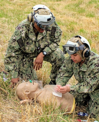 U.S. Navy Hospital Corpsman 3rd Class Dominique Heath, left, observes Hospitalman Stephany Compozano Garzon as she applies an occlusive chest seal to a training mannequin during a Tactical Combat Casualty Care (TCCC) evolution. The practical scenario tested critical airway and respiration interventions under the MARCH algorithm, including nasopharyngeal airway (NPA) placement and chest trauma management. The evolution is part of Navy Medicine Readiness and Training Command (NMRTC) Patuxent River’s "Warrior Wednesday" initiative, designed to reinforce hands-on trauma skills and enhance expeditionary readiness across the command.