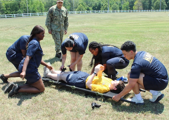 U.S. Navy Hospital Corpsman 1st Class Antonio Armenteros, center background, mentors medical personnel as they execute a tactical litter carry during a Tactical Combat Casualty Care (TCCC) evolution at Naval Support Facility (NSF) Indian Head, Maryland. The joint training scenario—combining personnel from Navy Medical Readiness and Training Unit (NMRTU) Dahlgren, NMRTC-Detachment Indian Head, and NMRTC-Detachment Joint Base Andrews—was held during a special "Warrior Wednesday" block commemorating the 128th Navy Hospital Corpsman Birthday. Under Armenteros' guidance, the drill reinforced patient movement techniques, team coordination, and field transport protocols, honoring the rating's heritage through hands-on operational readiness training.