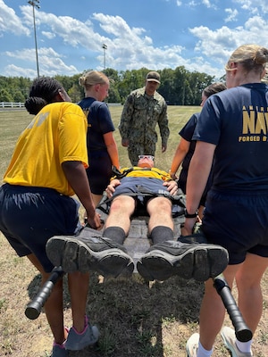 U.S. Navy Hospital Corpsman 1st Class Antonio Armenteros, center background, mentors medical personnel as they execute a tactical litter carry during a Tactical Combat Casualty Care (TCCC) evolution at Naval Support Facility (NSF) Indian Head, Maryland. The joint training scenario—combining personnel from Navy Medical Readiness and Training Unit (NMRTU) Dahlgren, NMRTC-Detachment Indian Head, and NMRTC-Detachment Joint Base Andrews—was held during a special "Warrior Wednesday" block commemorating the 128th Navy Hospital Corpsman Birthday. Under Armenteros' guidance, the drill reinforced patient movement techniques, team coordination, and field transport protocols, honoring the rating's heritage through hands-on operational readiness training