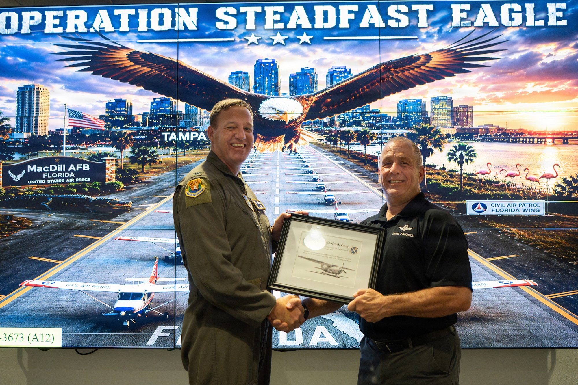 U.S. Air Force Col. Kevin Eley, 6th Air Refueling Wing commander, receives a certificate of appreciation from Civil Air Patrol Col. David Panzera, Florida Wing commander, at MacDill Air Force Base, Florida, July 25, 2026. This presentation recognized the partnership between the 6th ARW and its U.S. Air Force Auxiliary partners as they prepared for joint domestic operations. (U.S. Air Force Photo by Airman 1st Class Helen Ly)