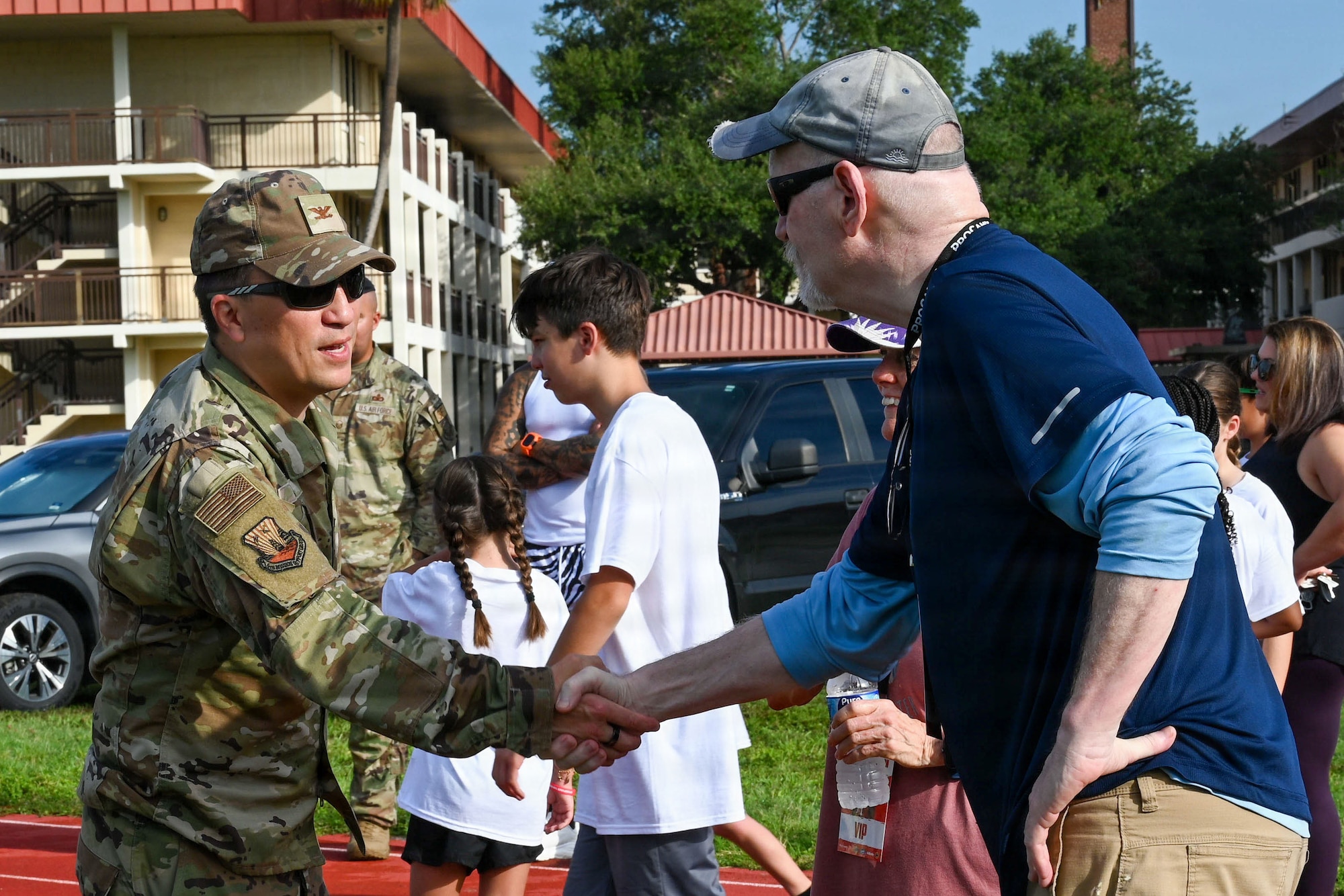 U.S. Air Force Col. BJ Lim, 6th Mission Support Group commander, greets John White, a volunteer, during the Prosports NFL Football camp on MacDill Air Force Base, Florida, July 25, 2026. A’Shawn Robinson, Tampa Bay Buccaneers defensive end, hosted the camp to support military families and provide fundamental coaching to military dependents. (U.S. Air Force photo by Airman 1st Class Alexis McDonnell)