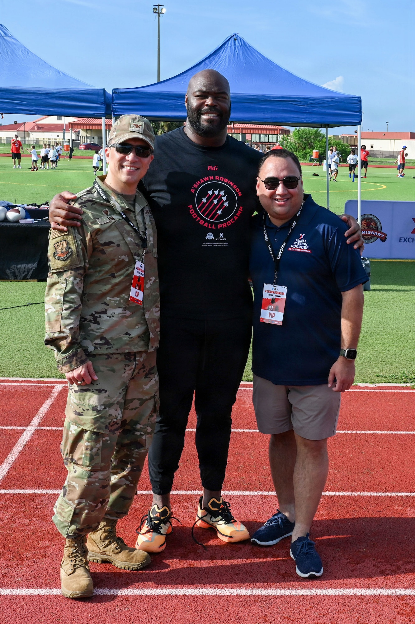U.S. Air Force Col. BJ Lim, 6th Mission Support Group commander, right, A’Shawn Robinson, Tampa Bay Buccaneers defensive end, middle, and Andrew Defelice, MacDill Base exchange manager, pose for a photo during the Prosports NFL Football camp on MacDill Air Force Base, Florida, July 25, 2026. Robinson hosted the NFL Football Procamp to support the local military community and provide fundamental coaching to dependents. (U.S. Air Force photo by Airman 1st Class Alexis McDonnell)