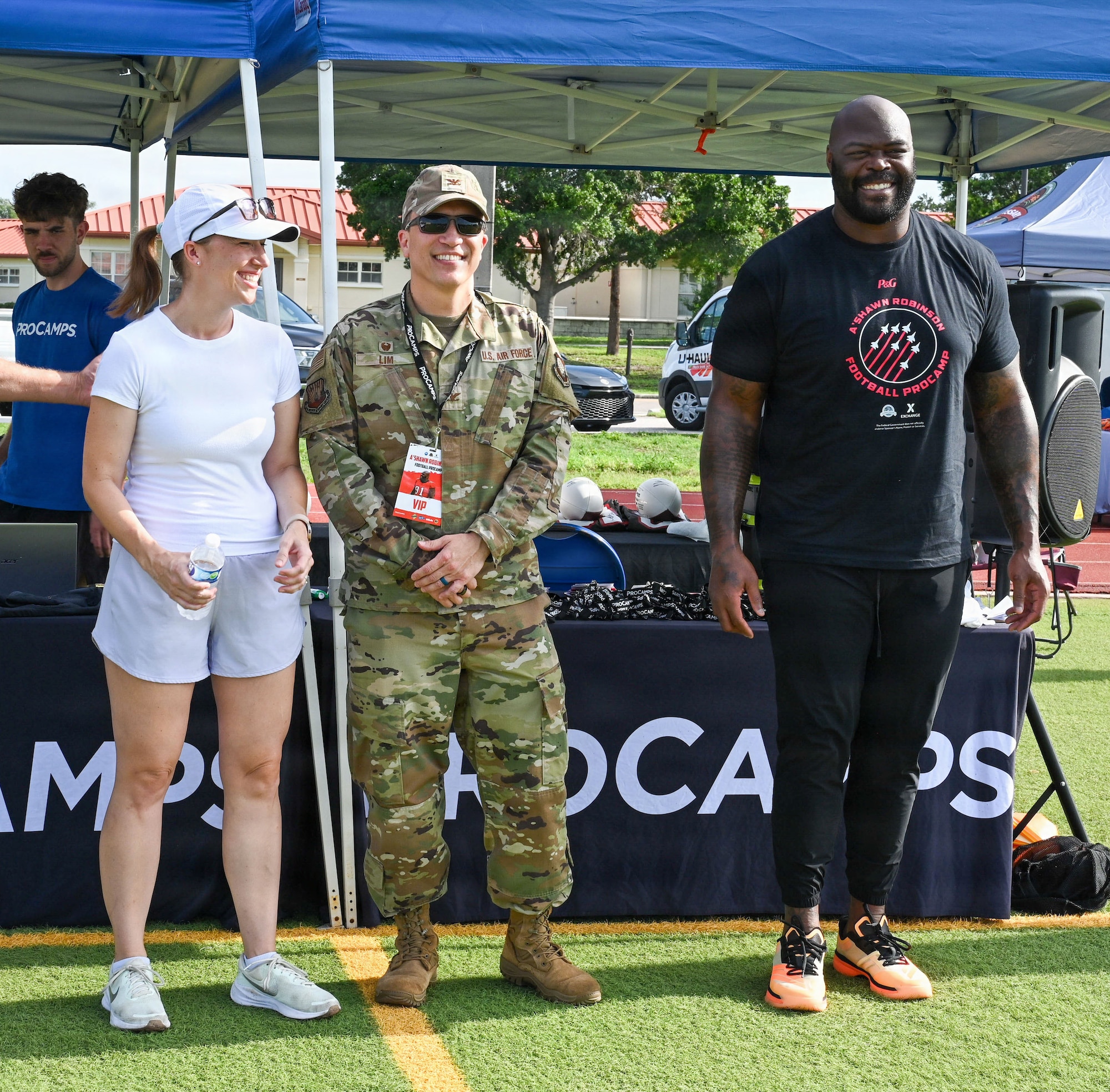 Jennifer Lim, military spouse, right, U.S. Air Force Col. BJ Lim, 6th Mission Support Group commander, middle, and A’Shawn Robinson, Tampa Bay Buccaneers defensive end, prepare to give opening remarks during the NFL Football Procamp hosted on MacDill Air Force Base, Florida, July 25, 2026. Robinson hosted the NFL Football Procamp to support the local military community and provide fundamental coaching to dependents. (U.S. Air Force photo by Airman 1st Class Alexis McDonnell)