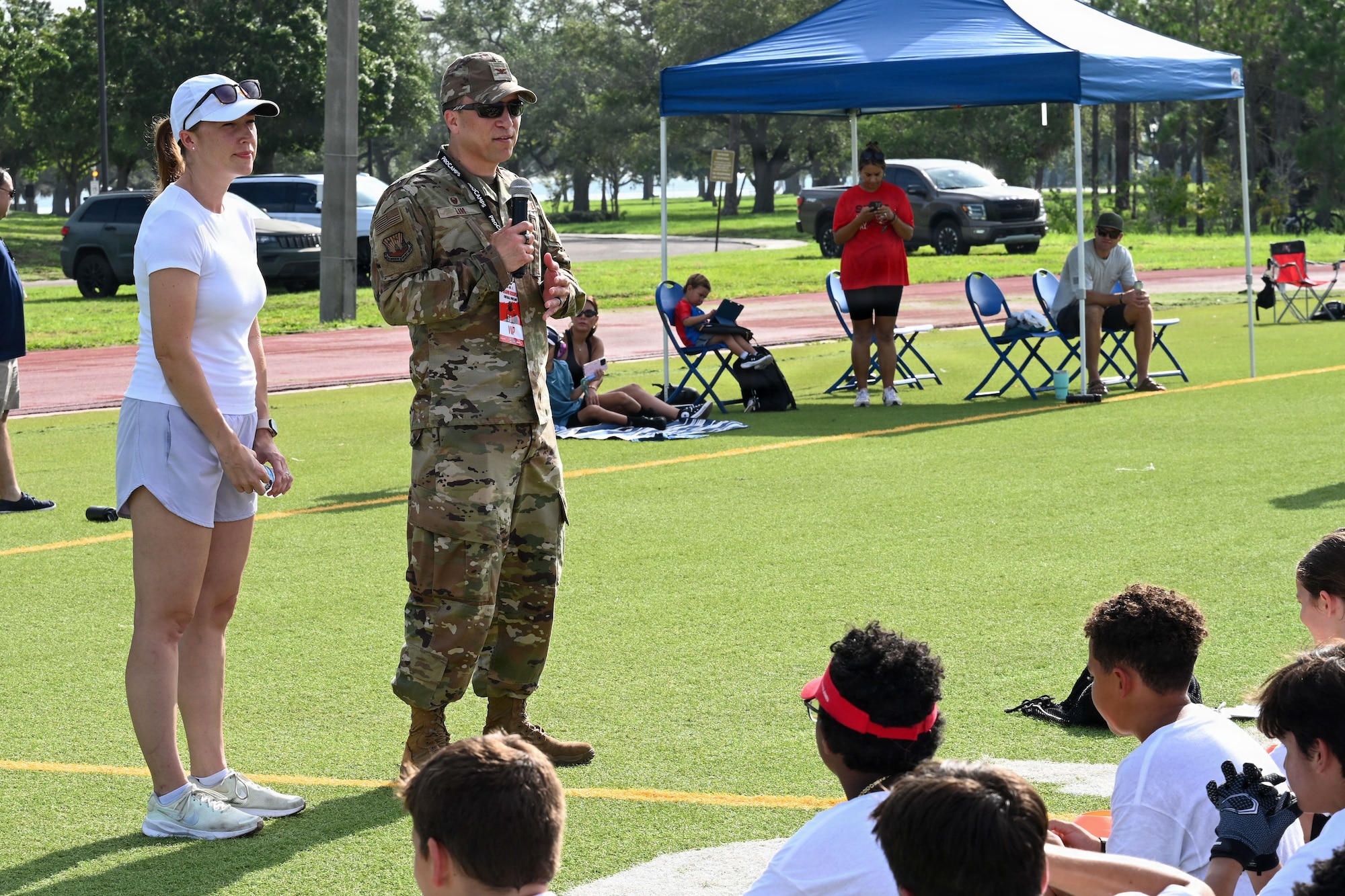 Jennifer Lim, military spouse, right, and U.S. Air Force Col. BJ Lim, 6th Mission Support Group commander, give opening remarks during the NFL Football Procamp hosted on MacDill Air Force Base, Florida, July 25, 2026. The football camp was hosted by A’Shawn Robinson, Tampa Bay Buccaneers defensive end, to support local military families and provide fundamental coaching. (U.S. Air Force photo by Airman 1st Class Alexis McDonnell)