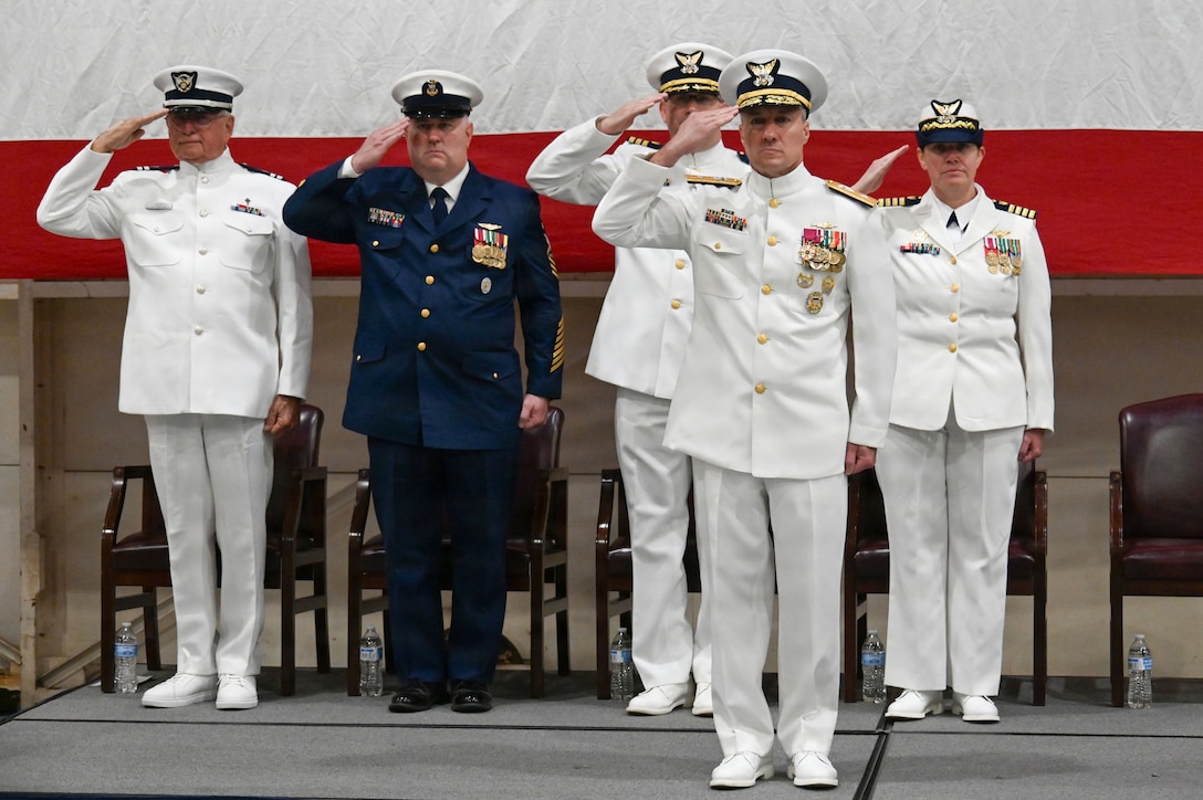 The official party salutes during the playing of the national anthem during a change-of-command ceremony held at Air Station Savannah in Georgia, July, 31, 2026; the official party left to right: Coast Guard Auxiliary Chaplain Sam Davis, Master Chief Petty Officer James Murray, Cmdr. Zachary Wiest, Rear Adm. Adam Chamie and Capt. Maegan Schwartz. (U.S. Coast Guard photo by Petty Officer 1st Class Brandon Hillard)