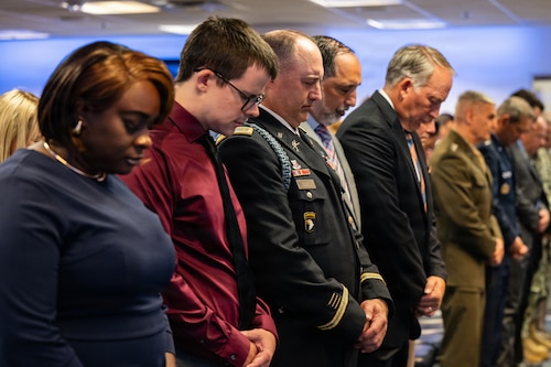 A crowd bowing their heads during a ceremony.
