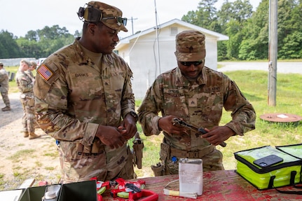 (From right) U.S. Army Sgts. Kirk Banks and McClifford Genois, military police, 273rd Military Police Company, 372nd Enhanced Military Battalion, 260th Special Purpose Brigade, applies cleaner, lubricant and preservative (CLP) on a pistol before conducting marksmanship training at Fort A.P. Hill, Virginia, July 28, 2026. This training was part of a multi-day advanced marksmanship exercise focused on enhancing individual and team weapons proficiency while preparing soldiers for contingency operations.