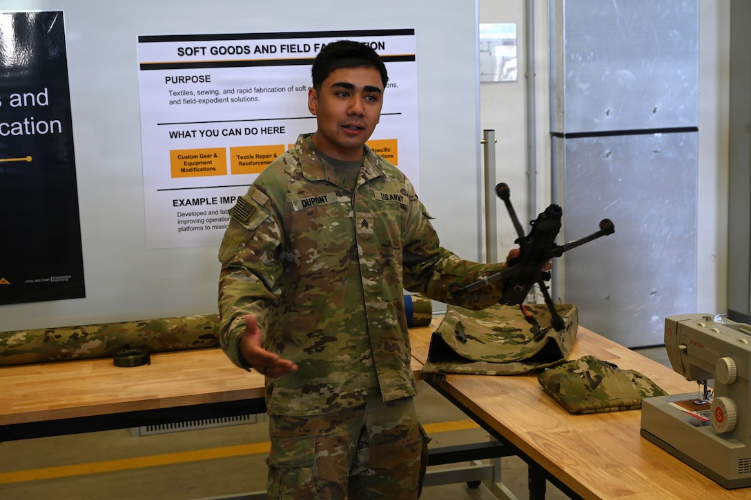 U.S. Army Sgt. Logan Dupont, assigned to Regimental Support Squadron, 2nd Cavalry Regiment, displays custom soft bags, designed and sewn by himself, to carry drones in the field environment, during an open house at the 7th Army Training Command's  Design Innovation Research and Testing  Lab, Grafenwoehr, Germany, 31 July 2026. The DIRT Lab serves as a collaborative hub connecting Soldiers, engineers, and researchers to turn field-identified challenges into tangible solutions. Leveraging technologies like 3D printing, advanced manufacturing, robotics, and drones, empowering Soldiers to rapidly prototype and test capabilities designed by those closest to the challenges. (U.S. Army photo by Kevin Sterling Payne)