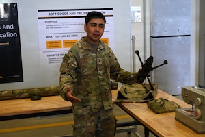 U.S. Army Sgt. Logan Dupont, assigned to Regimental Support Squadron, 2nd Cavalry Regiment, displays custom soft bags, designed and sewn by himself, to carry drones in the field environment, during an open house at the 7th Army Training Command's  Design Innovation Research and Testing  Lab, Grafenwoehr, Germany, 31 July 2026. The DIRT Lab serves as a collaborative hub connecting Soldiers, engineers, and researchers to turn field-identified challenges into tangible solutions. Leveraging technologies like 3D printing, advanced manufacturing, robotics, and drones, empowering Soldiers to rapidly prototype and test capabilities designed by those closest to the challenges. (U.S. Army photo by Kevin Sterling Payne)