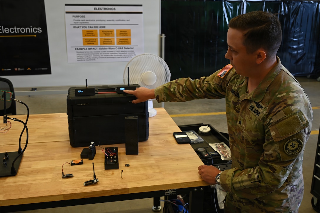 U.S. Army Sgt. Ryan Minton, assigned to Regimental Support Squadron, 2nd Cavalry Regiment, displays a custom drone detection device which he designed and built for Soldiers to carry in the field environment, during an open house at the 7th Army Training Command's  Design Innovation Research and Testing  Lab, Grafenwoehr, Germany, 31 July 2026. The DIRT Lab serves as a collaborative hub connecting Soldiers, engineers, and researchers to turn field-identified challenges into tangible solutions. Leveraging technologies like 3D printing, advanced manufacturing, robotics, and drones, empowering Soldiers to rapidly prototype and test capabilities designed by those closest to the challenges. (U.S. Army photo by Kevin Sterling Payne)