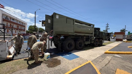 Soldiers with the Puerto Rico National Guard distribute potable water to residents from a military water tanker truck at a community distribution point.