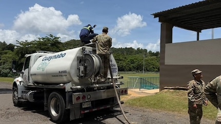U.S. Army Soldiers work alongside a civilian contractor atop a Guaynabo City municipal water tanker truck (K-210SS) during a water distribution operation at an unidentified facility in Puerto Rico.