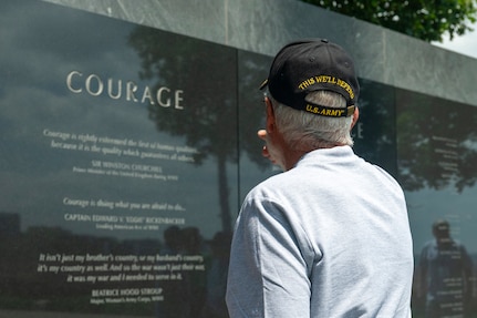 A U.S. Army veteran faces and points at a granite inscription at the Air Force Memorial
