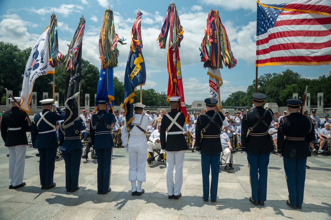 Joint Armed Forces Color Guard stand in front of veterans at the World World II memorial holding the colors