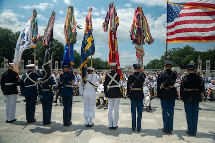 Joint Armed Forces Color Guard stand in front of veterans at the World World II memorial holding the colors