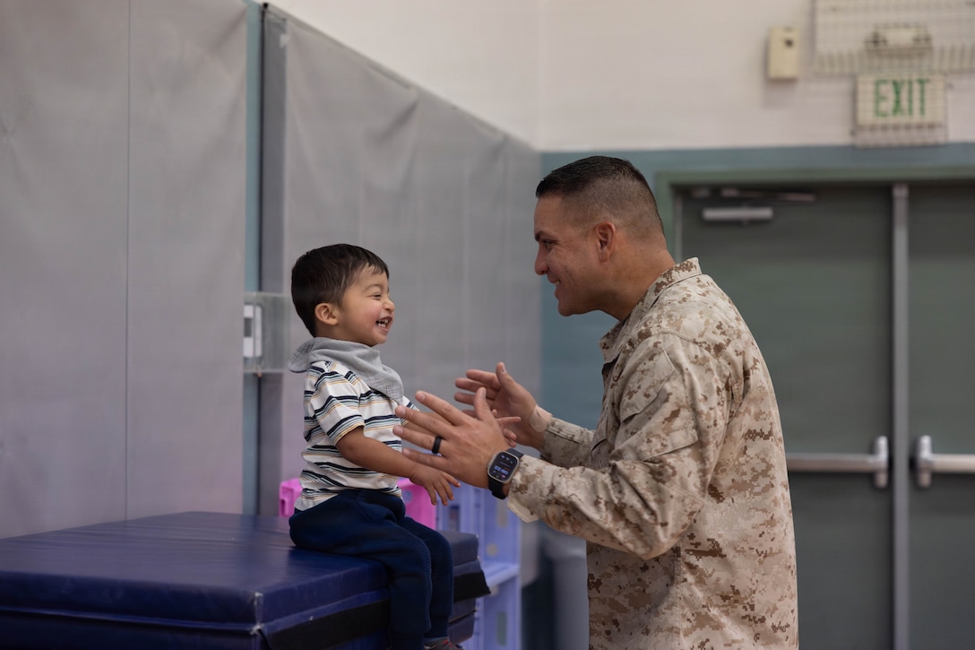U.S. Navy Lt. Nephtali Ortega, a Puerto Rico native and chaplain with 2nd battalion, 7th Marine Regiment, 1st Marine Division, entertains his son during the Presidential Fitness Test at Marine Corps Air Ground Combat Center Community Center, Twentynine Palms, California, July 23, 2026. The Presidential Fitness Test is for children ages 6 to 18 and encourages building strength, endurance, and healthy habits while striving for personal improvement. (U.S. Marine Corps photo by Lance Cpl. Cody Fitzgerald)