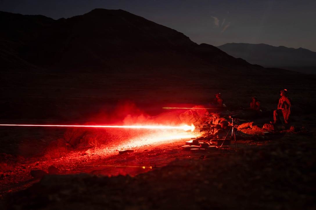 Marines on the ground fire machine guns. They are in the mountains at night.