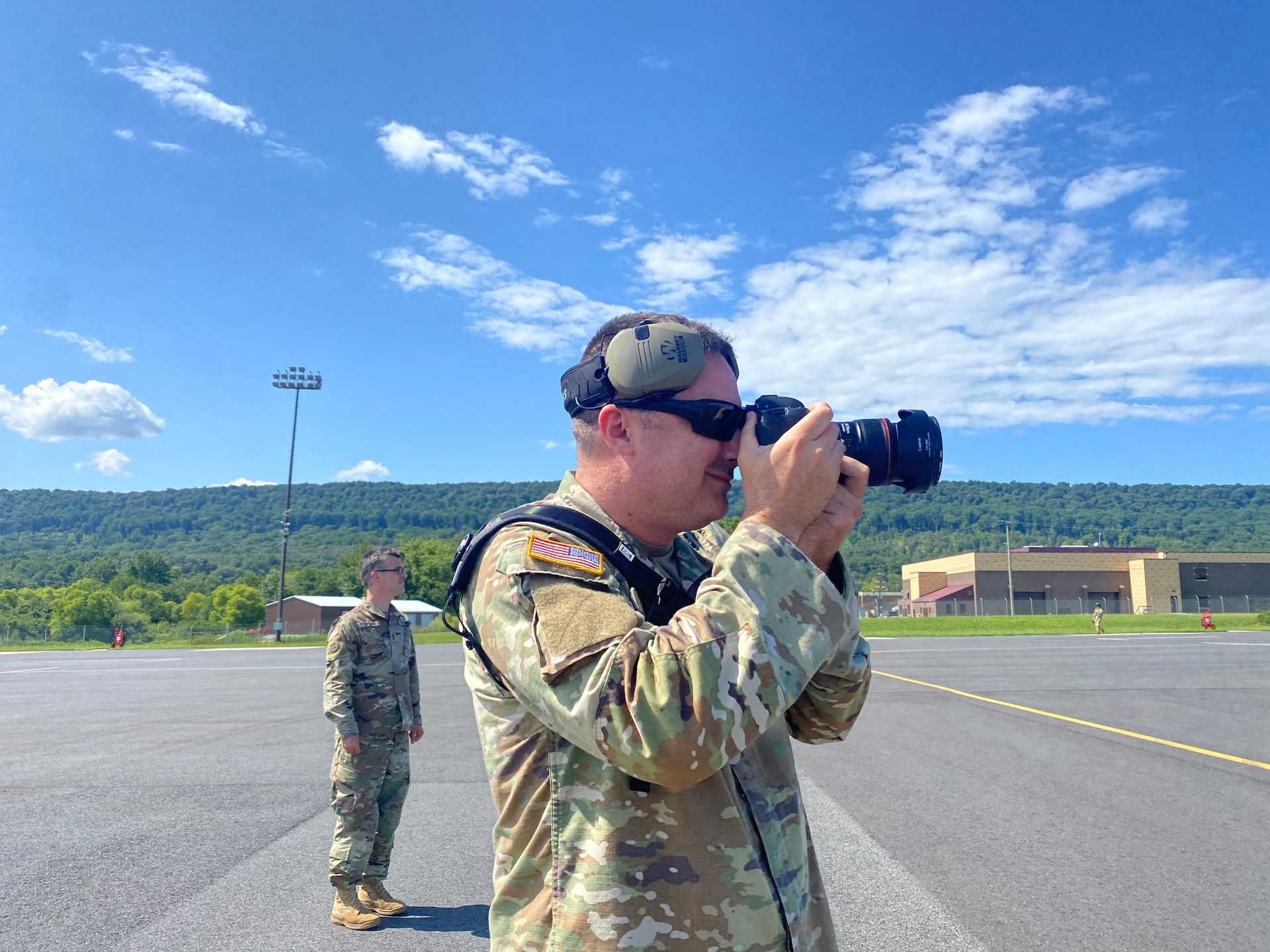 U.S. Army Sgt. 1st Class Brandon Nelson, chief public affairs specialist with the 109th Mobile Public Affairs Detachment, 213th Regional Support Group, takes a photo of a helicopter on Muir Army Heliport at Fort Indiantown Gap, Aug. 1, 2023. (U.S. Army National Guard photo by Maj. Travis Mueller)
