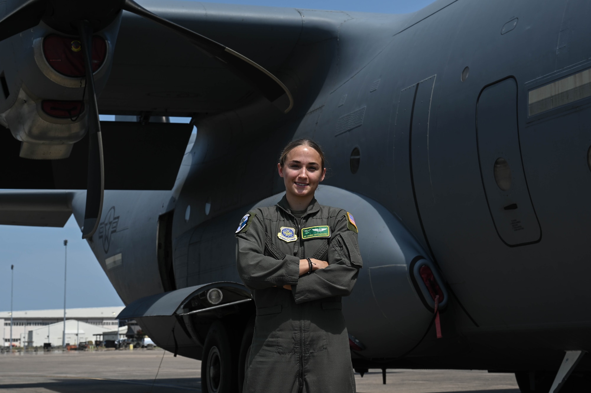 Woman stands on front of a C-130J Super Hercules Aircraft with arms crossed.
