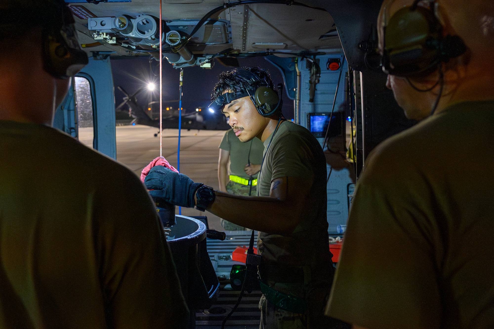 U.S. Air Force Senior Airman Gabriel Magallano, 718th Aircraft Maintenance Squadron crew chief, inspects the rescue hoist system on an HH-60W Jolly Green II assigned to the 33rd Rescue Squadron during BB26-1 at Kadena Air Base, Japan, Aug. 3, 2026. Kadena Air Base's training is critical to deterring aggression and being ready to fight and win to protect the vital interests of the United States and Japan. (U.S. Air Force photo by Airman 1st Class Francisco Huerta)