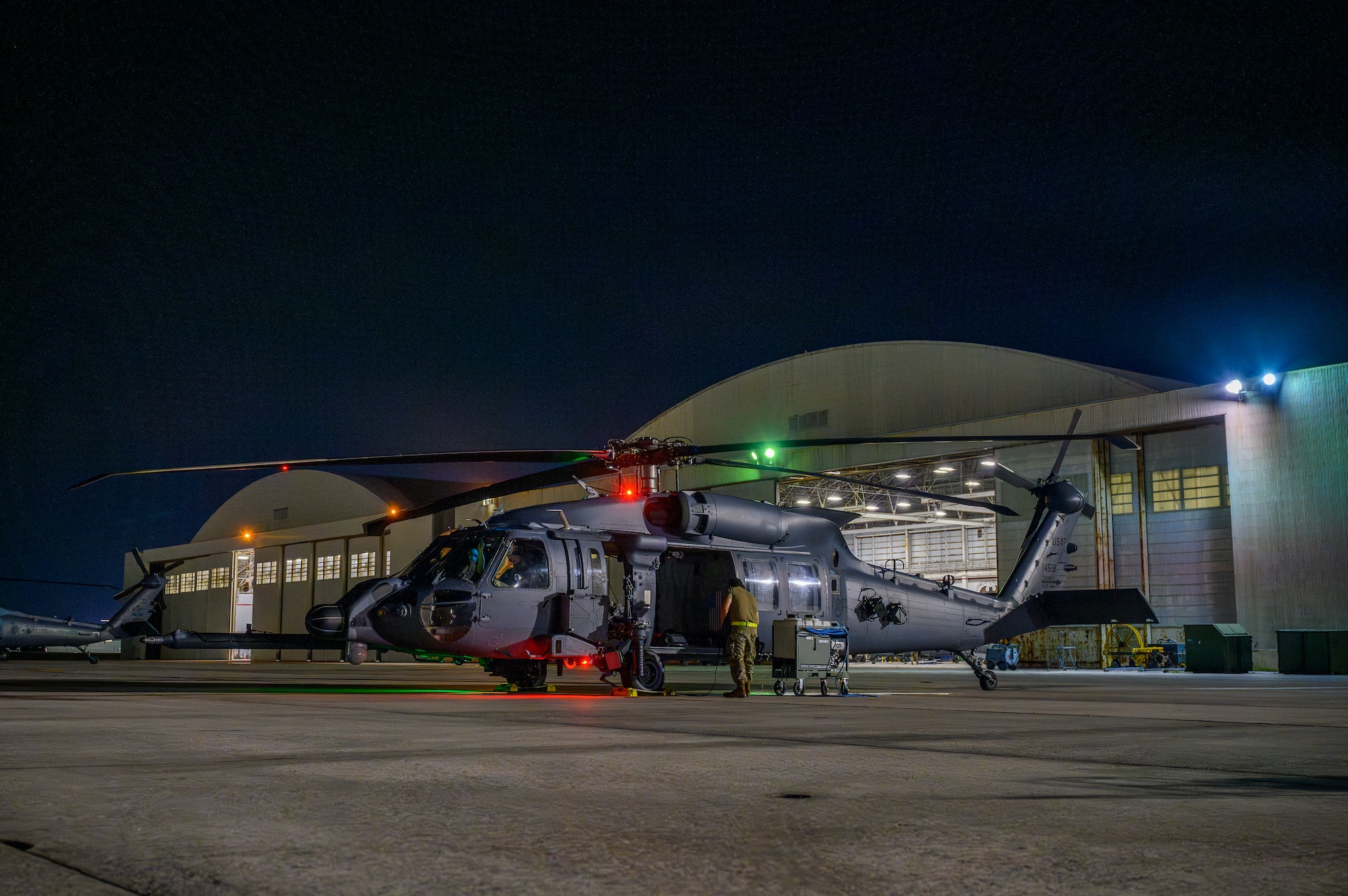 An HH-60W Jolly Green II assigned to the 33rd Rescue Squadron sits on the flightline with maintenance hangars in the background during BB26-1 at Kadena Air Base, Japan, Aug. 3, 2026. Kadena Air Base's training is critical to deterring aggression and being ready to fight and win to protect the vital interests of the United States and Japan. (U.S. Air Force photo by Airman 1st Class Francisco Huerta)
