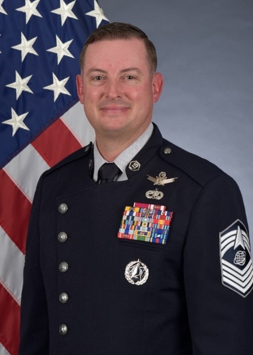 CHIEF MASTER SERGEANT JASON D. CHILDERS in uniform with flag