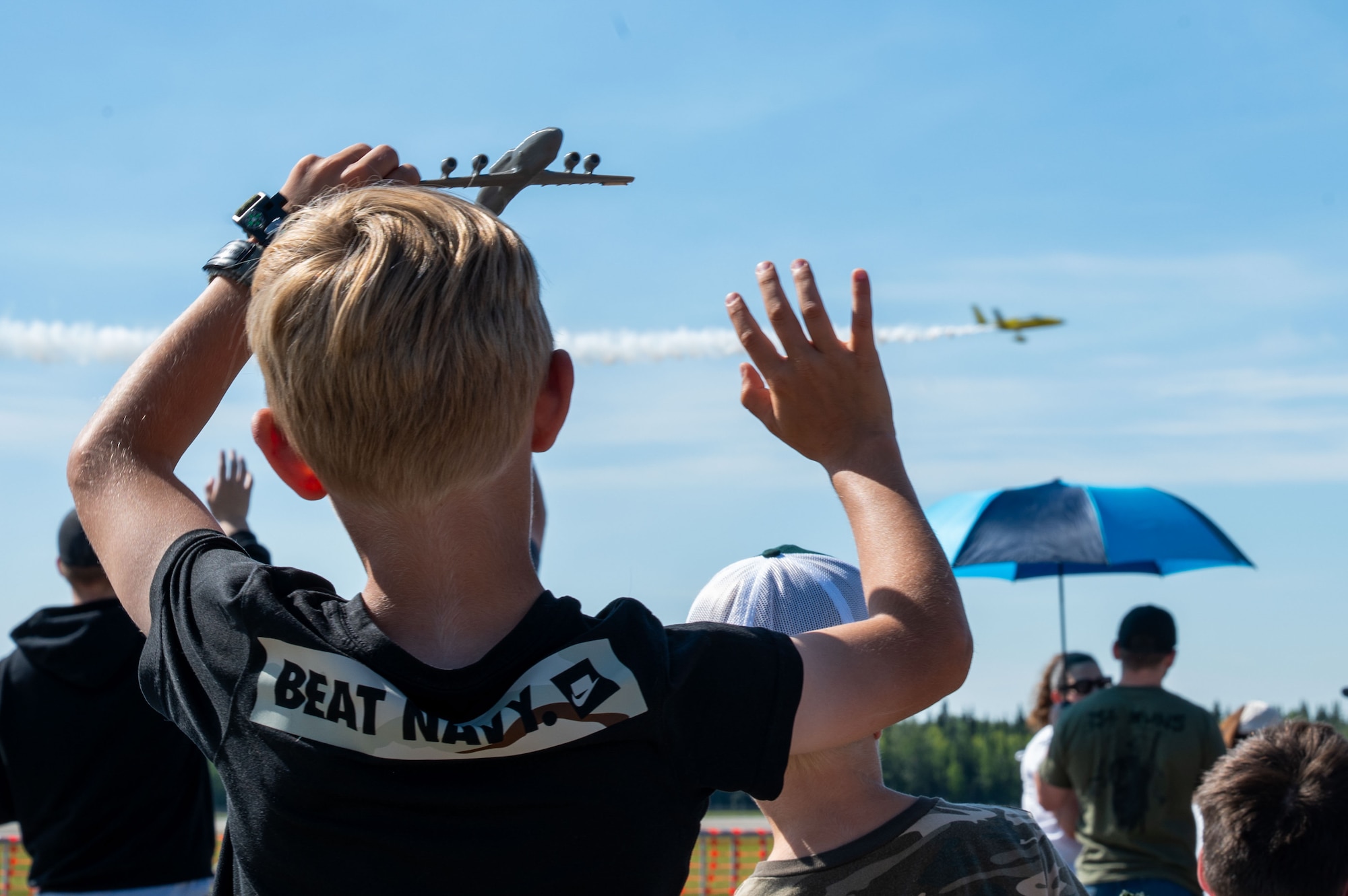 A child waves to an aircraft while watching an aerial demonstration during the Arctic Lightning Air Show at Eielson Air Force Base, Alaska, July 31, 2026.