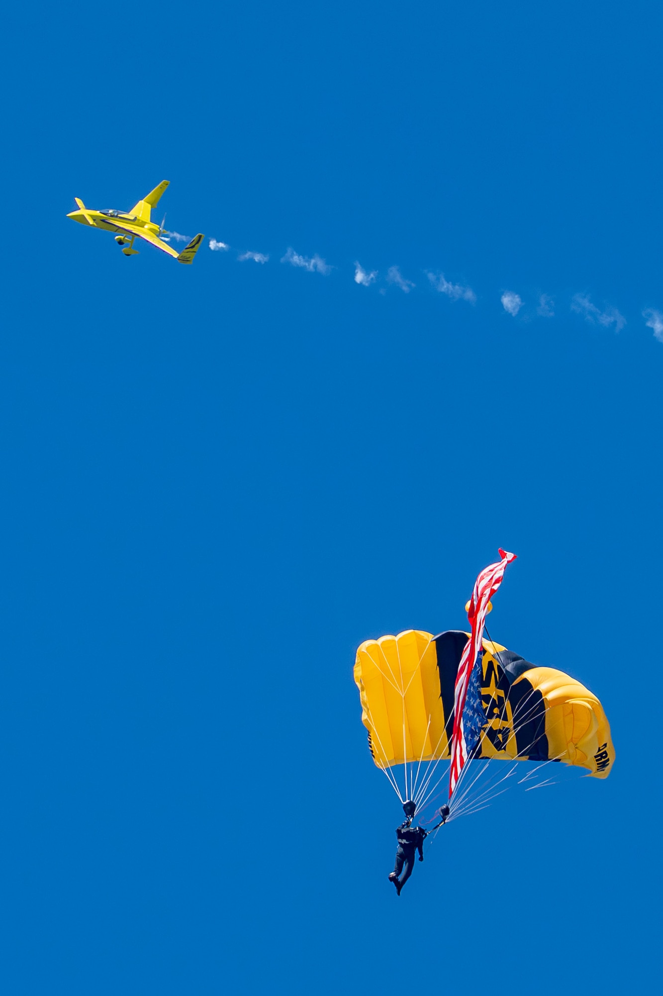 A member of the U.S. Army Golden Knights Parachute Team descends while Kyle Fowler, Aerosports owner and pilot, flies above during a demonstration at the Arctic Lightning Air Show at Eielson Air Force Base, Alaska, Aug. 1, 2026.